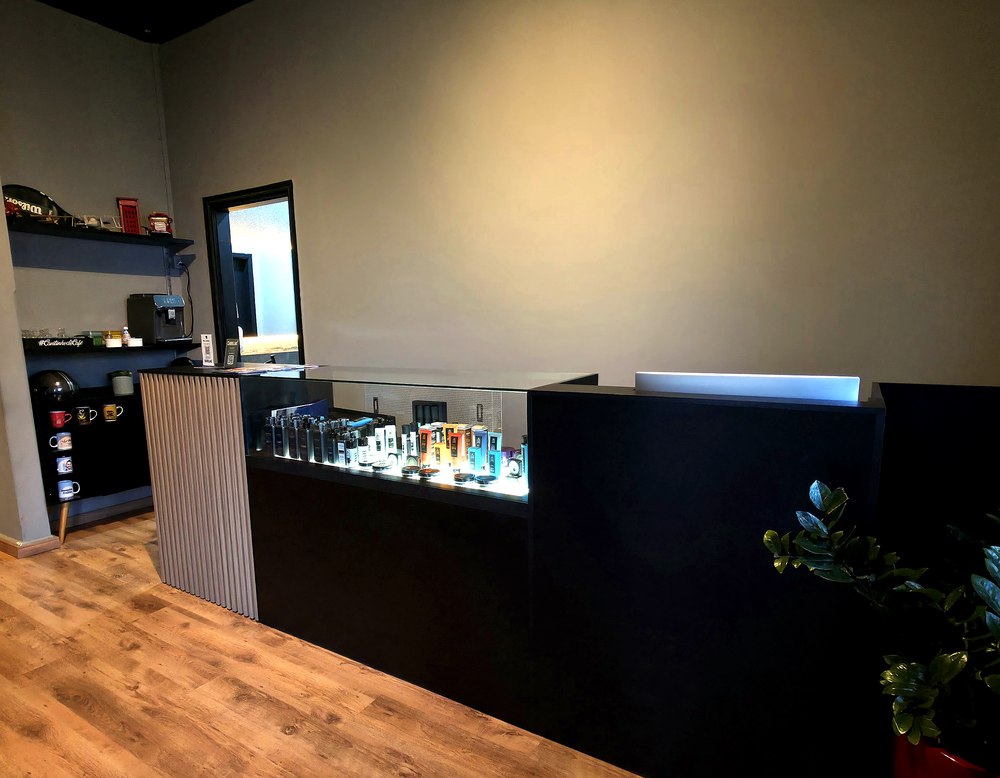 Recepção da Barbearia Cadillac com vitrine de produtos e área de café